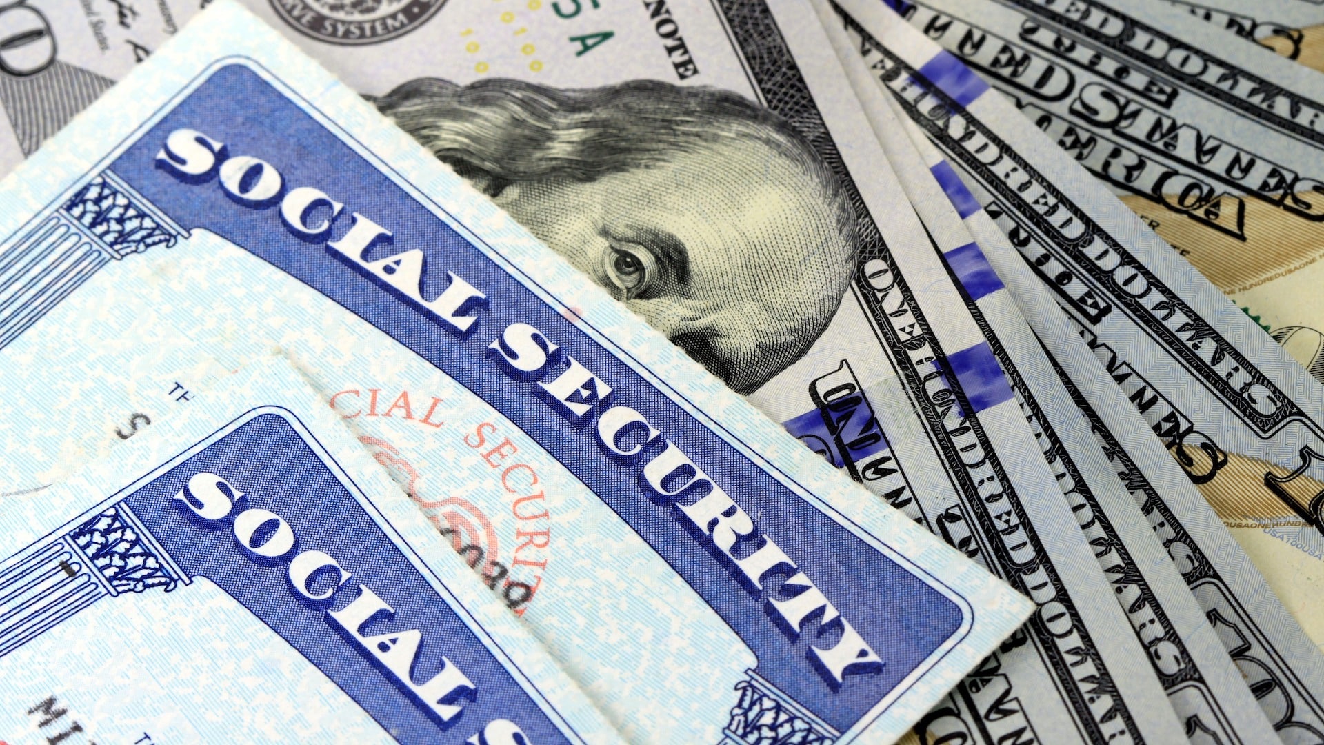 Social Security cards on top of $100 bills